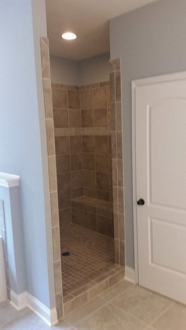 Glass shower enclosure with white tile walls, blue accent wall, and light-colored floor tiles in modern bathroom