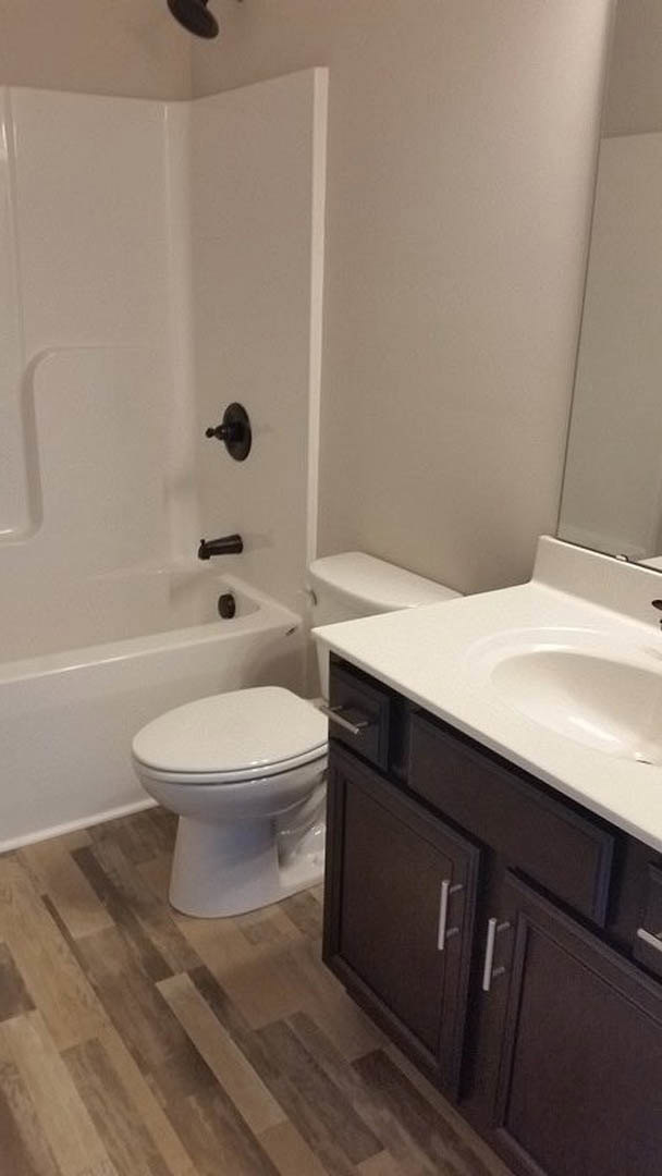 White porcelain toilet and bathtub beside a white sink, surrounded by light tile flooring and walls, chrome plumbing fixtures, and minimal bathroom accessories.