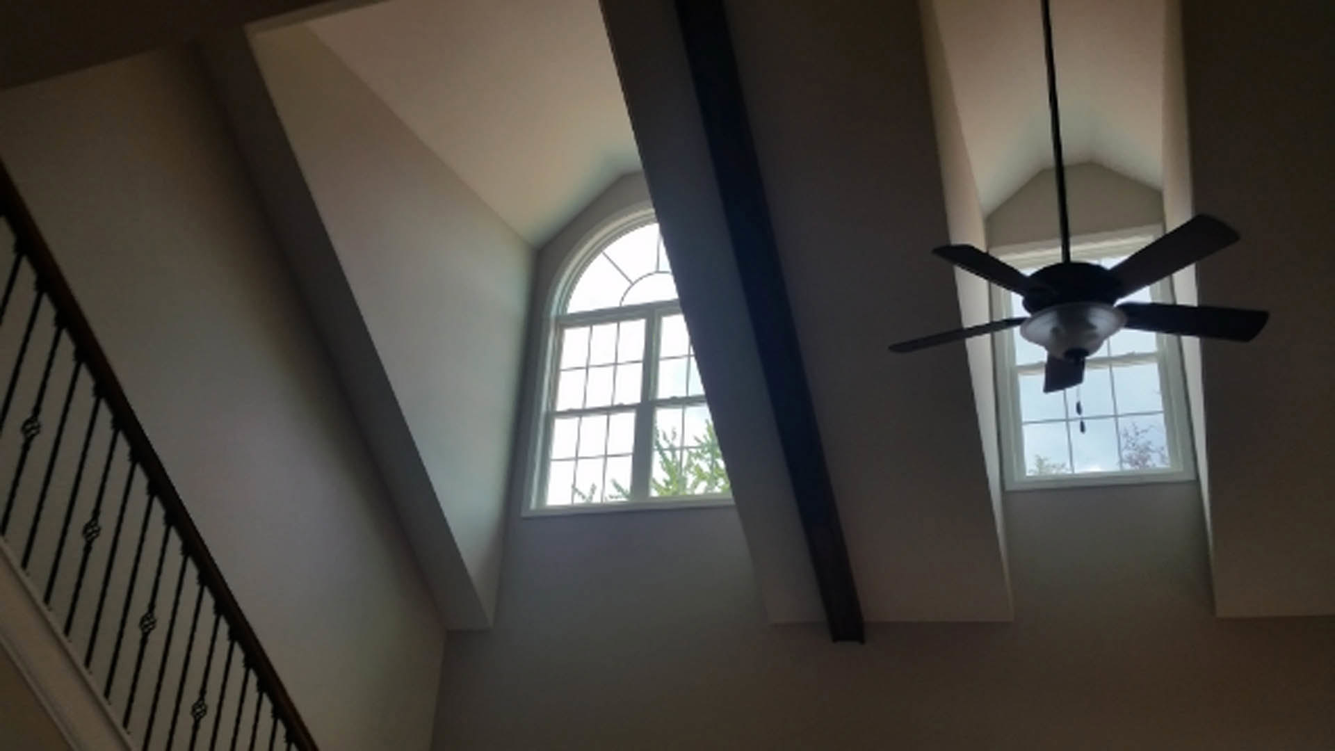 Ceiling fan with integrated light fixture mounted above hardwood floor in bright room with white-framed window and neutral walls