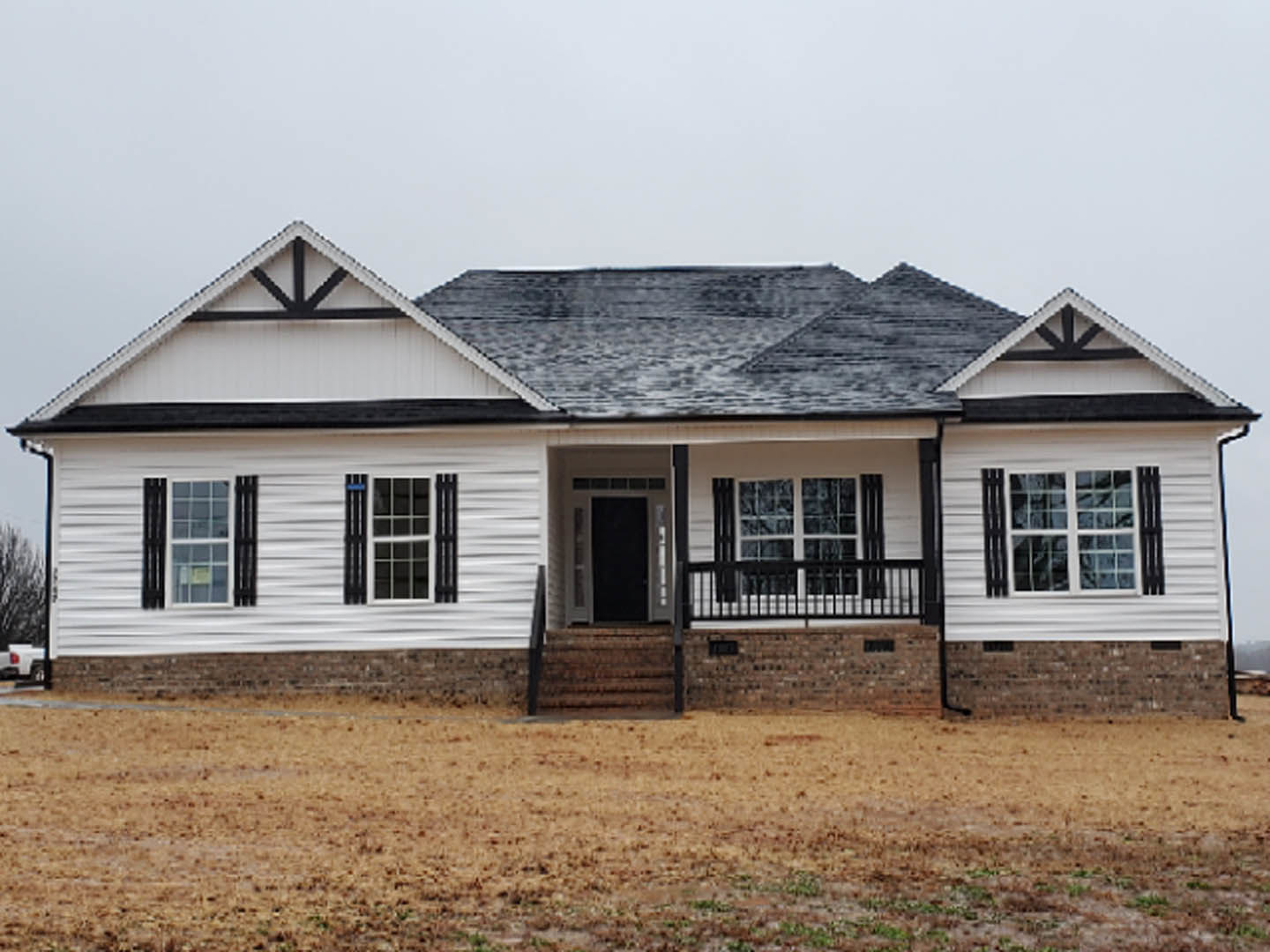 Two-story house with black roof, white siding, black shutters, black-framed windows, black front door, brown grass yard, and black metal fence