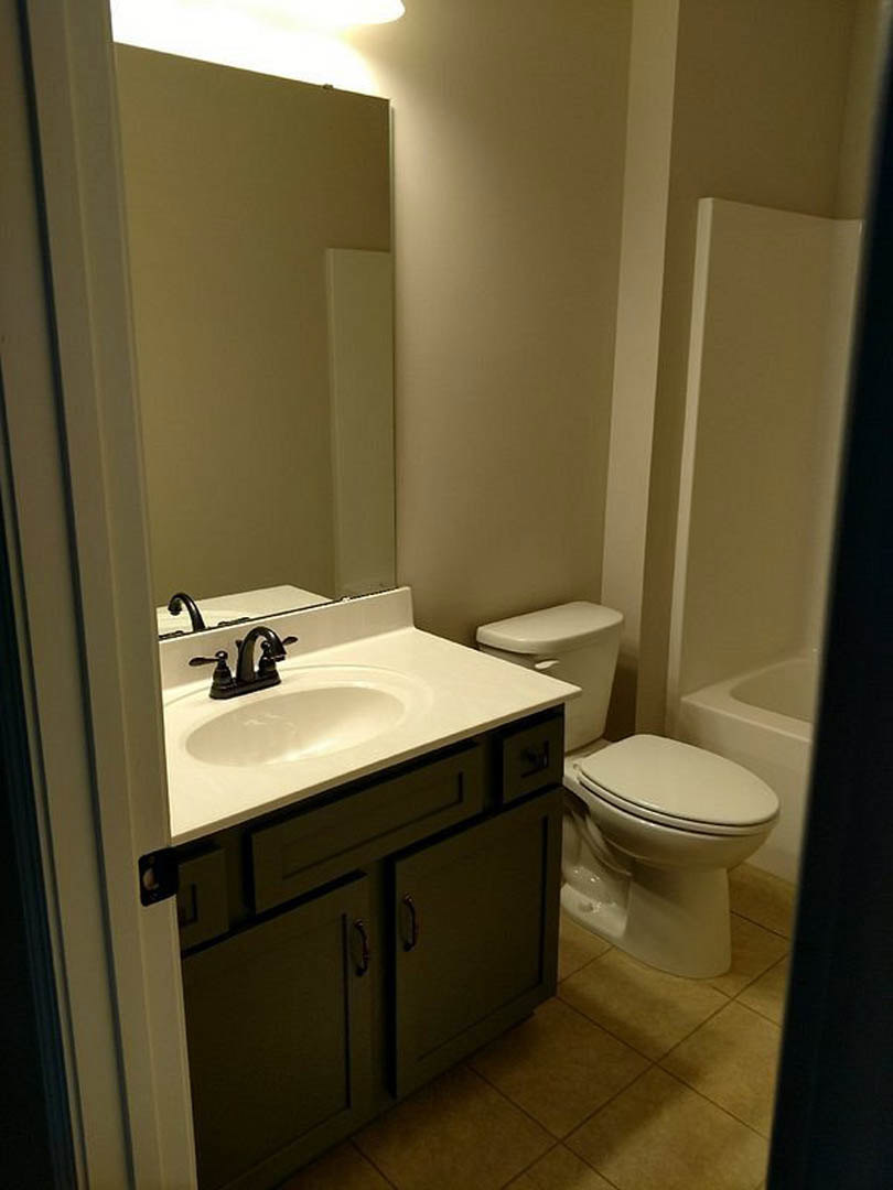Modern bathroom with white ceramic sink, chrome faucet, and matching white toilet against light gray tile walls