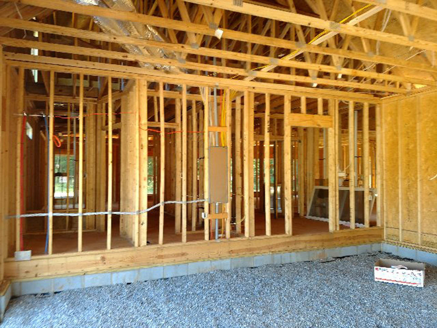 Exposed wood framing with beams, planks, and insulation around a window opening in a partially constructed home