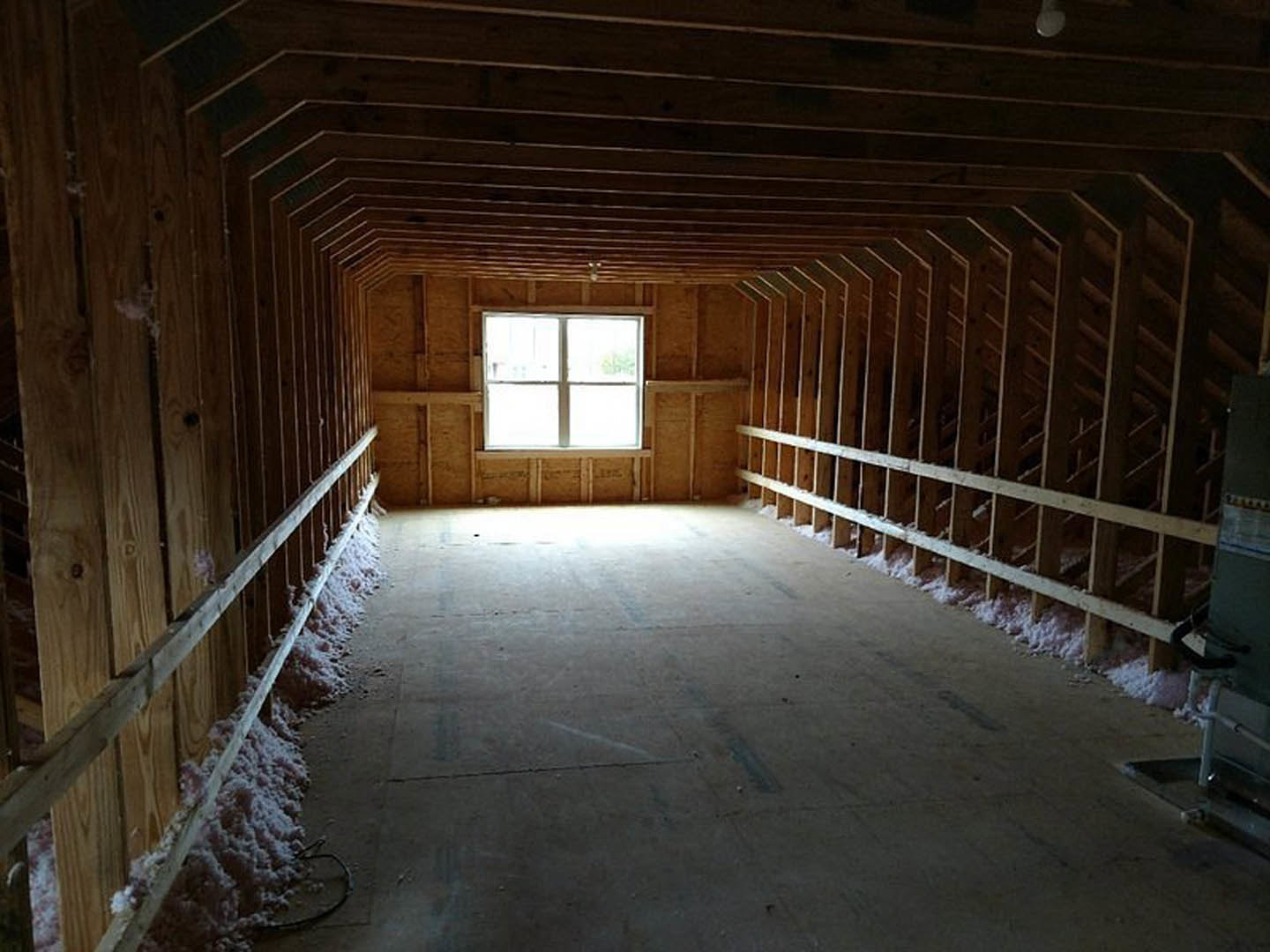 Sunlit room with dark wood paneling, exposed wooden beams on ceiling, large window casting light onto floor, snow visible outside.