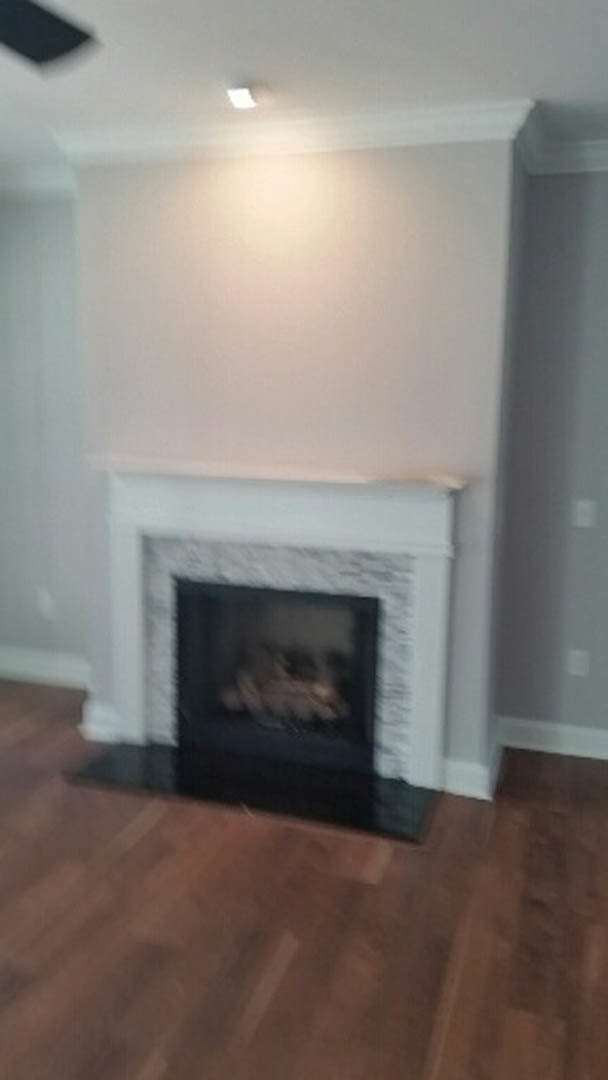 Modern living room with white walls, wood flooring, and a black wood-burning stove set into a central hearth