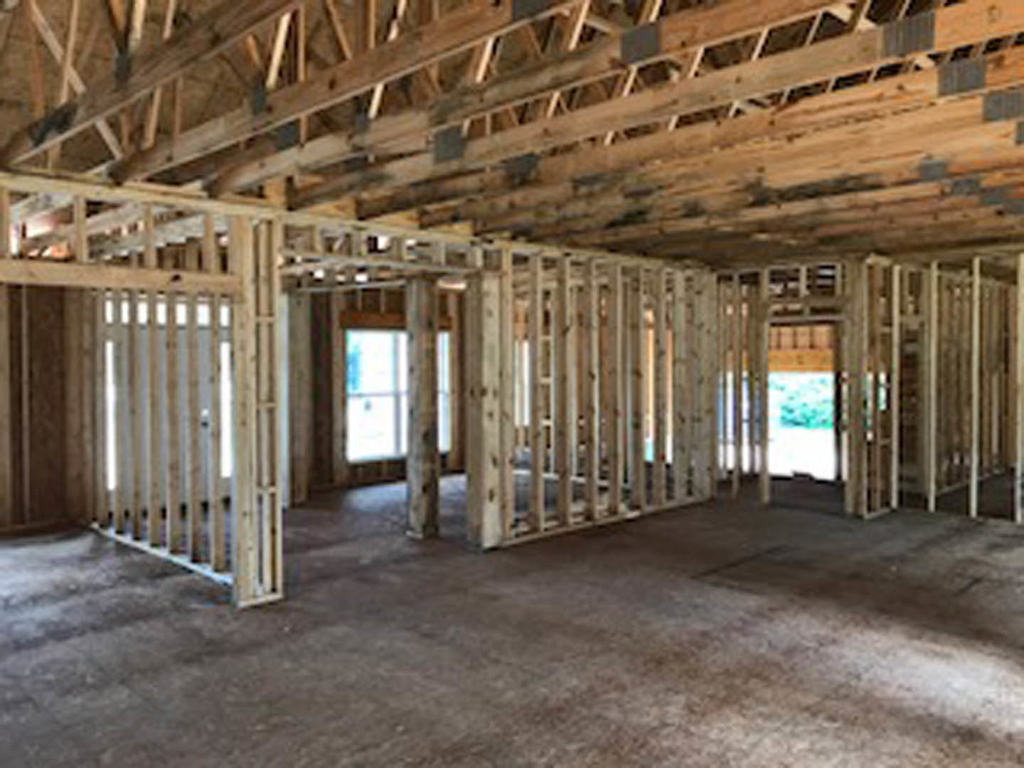 Unfinished room with exposed wood framing, ceiling beams, and partially visible window