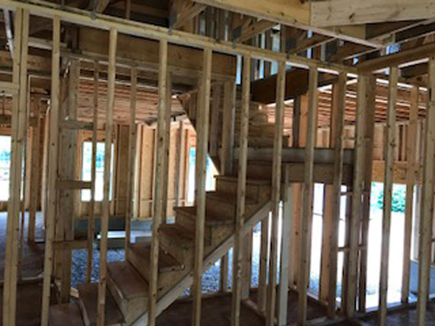 Wooden staircase with natural wood treads and risers, open railing, and exposed ceiling beams in a residential interior