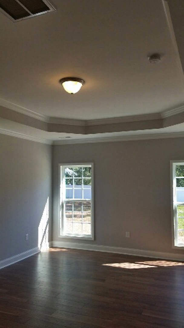 Wood plank flooring, white-framed window, plaster ceiling with recessed light fixture, neutral painted walls