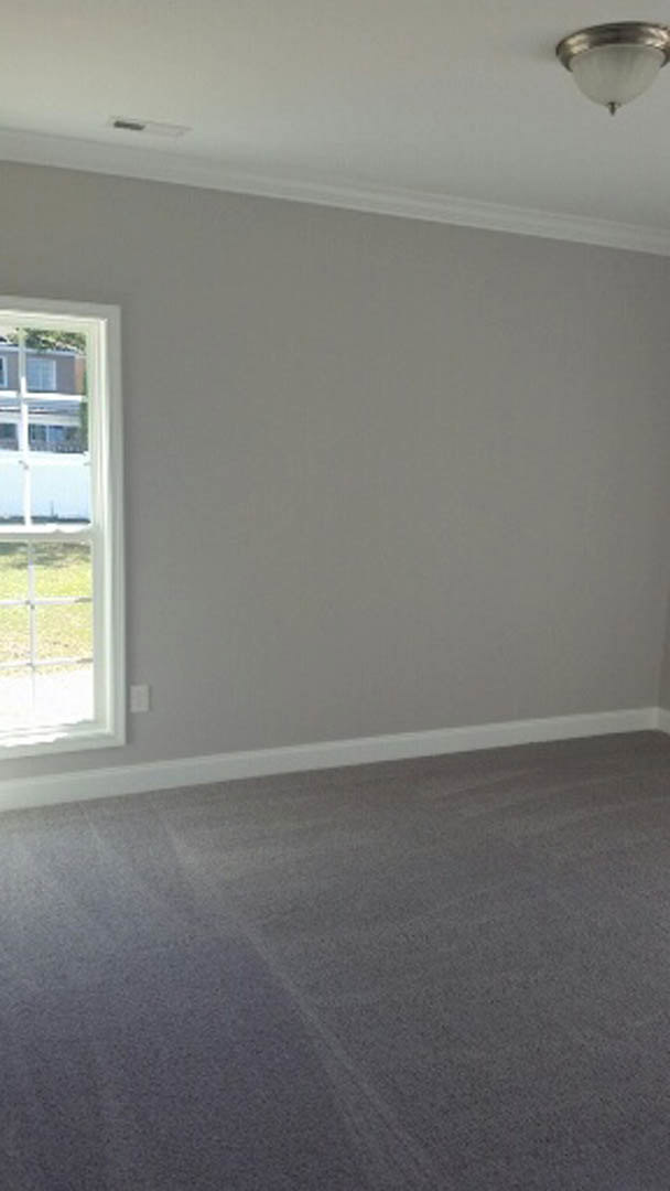 Carpeted room with white walls, white baseboards, large window overlooking ocean, ceiling fan, and recessed lighting
