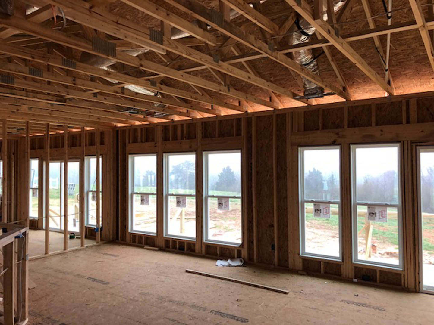 Spacious interior featuring exposed wood ceiling beams, large windows, and light wood flooring