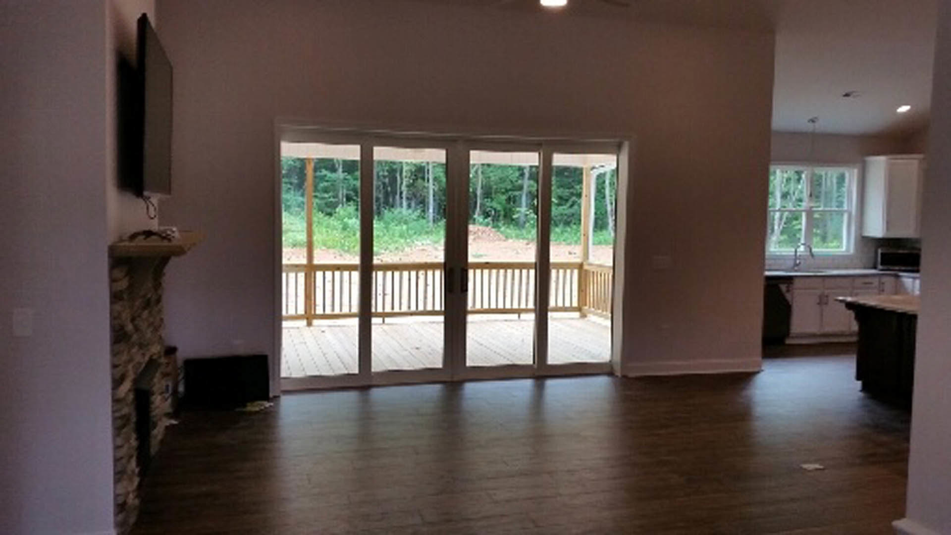Room with wood laminate flooring, white walls, and large sliding glass door leading outside