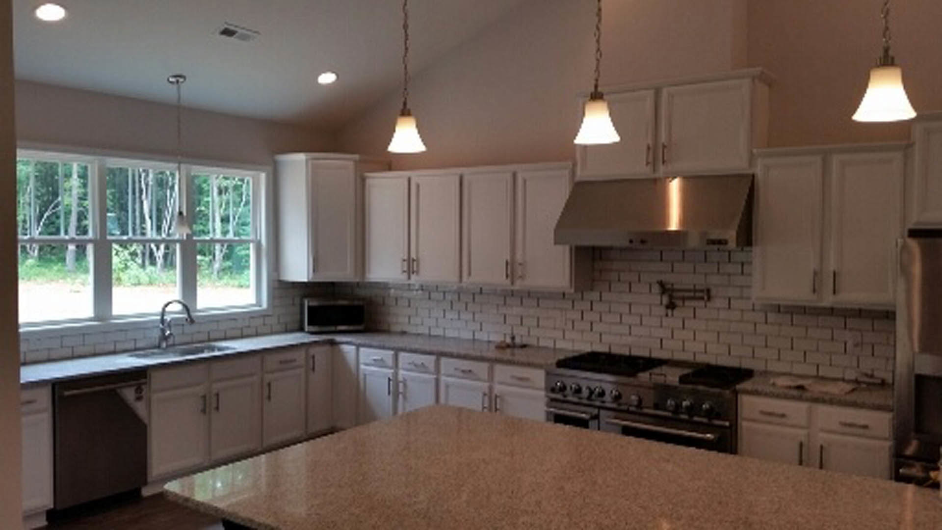 White shaker cabinets, stainless steel stove, light quartz countertops, undermount sink, brushed nickel hardware, tile backsplash