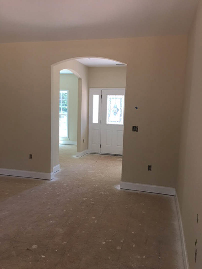 Hallway with white plaster walls, wood flooring, white door featuring stained glass window, and rectangular window letting in natural light