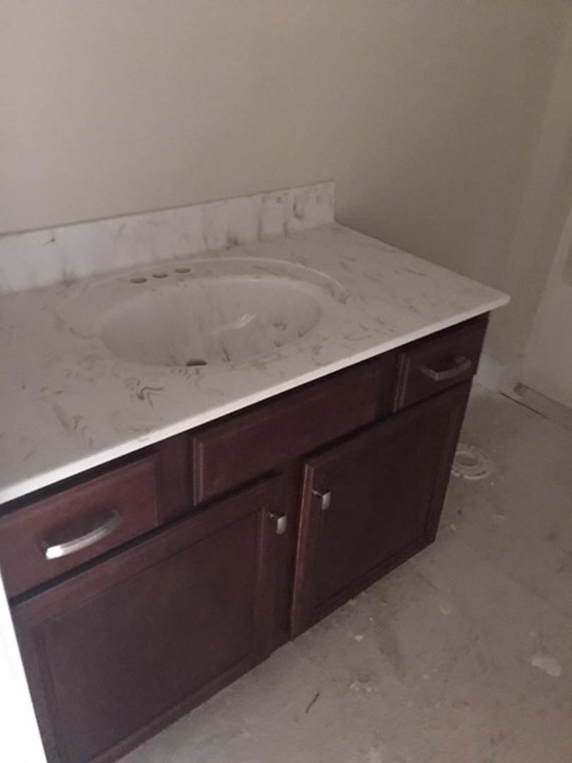 Marble countertop bathroom vanity with undermount sink, chrome faucet, and tile backsplash