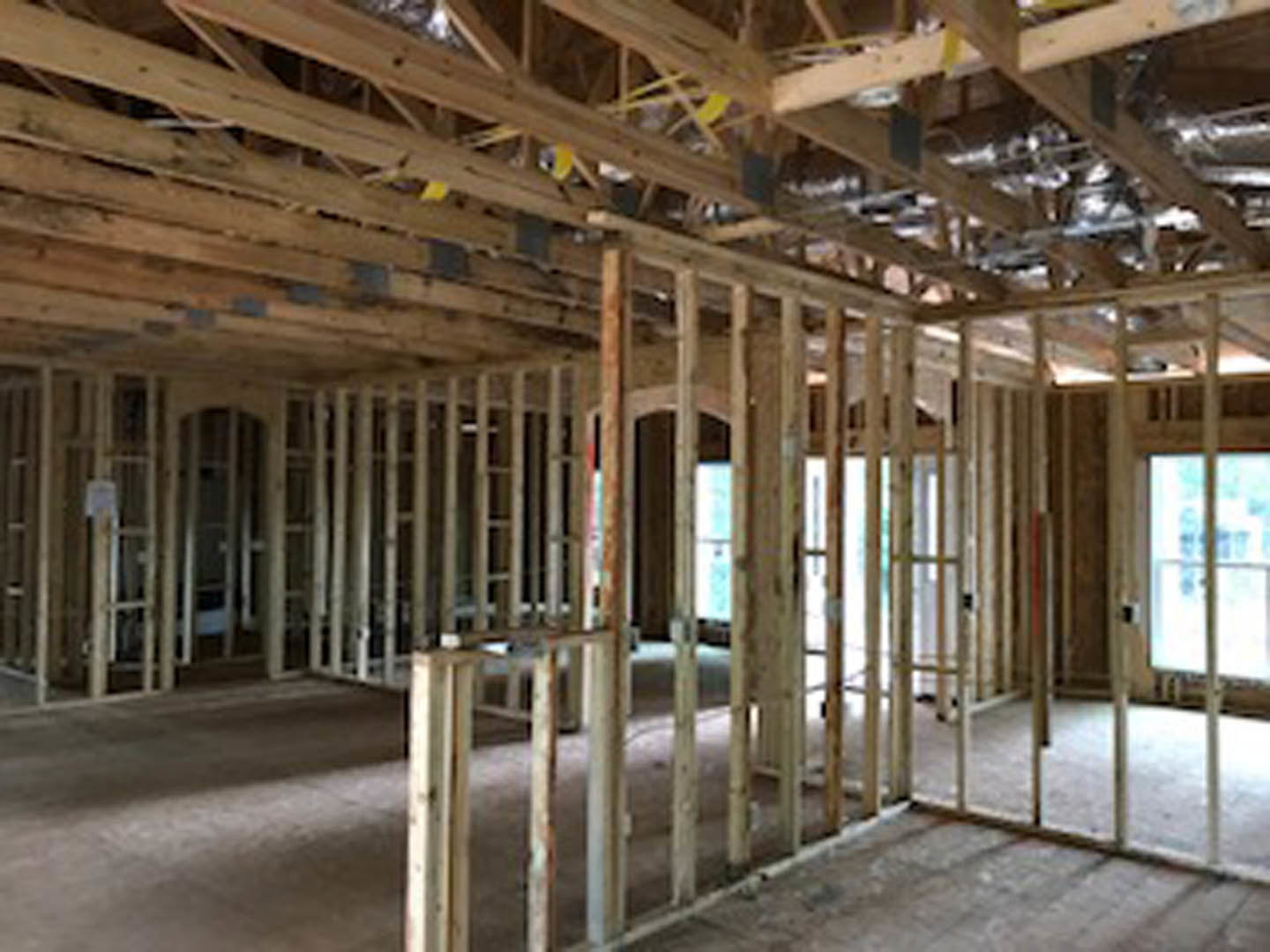 Living room with exposed wood ceiling beams, light hardwood floors, and a wooden door leading to an adjacent space.