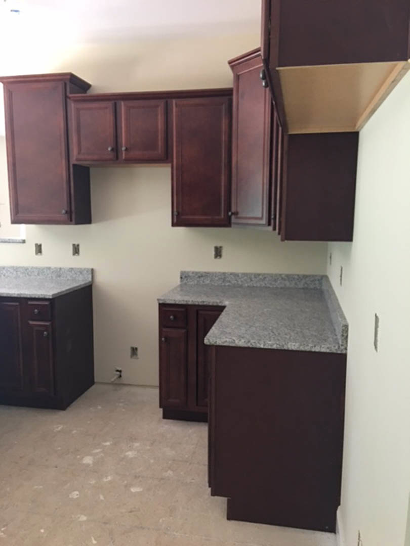 Kitchen featuring dark wood cabinets, granite countertops, stainless steel appliances, and tile backsplash