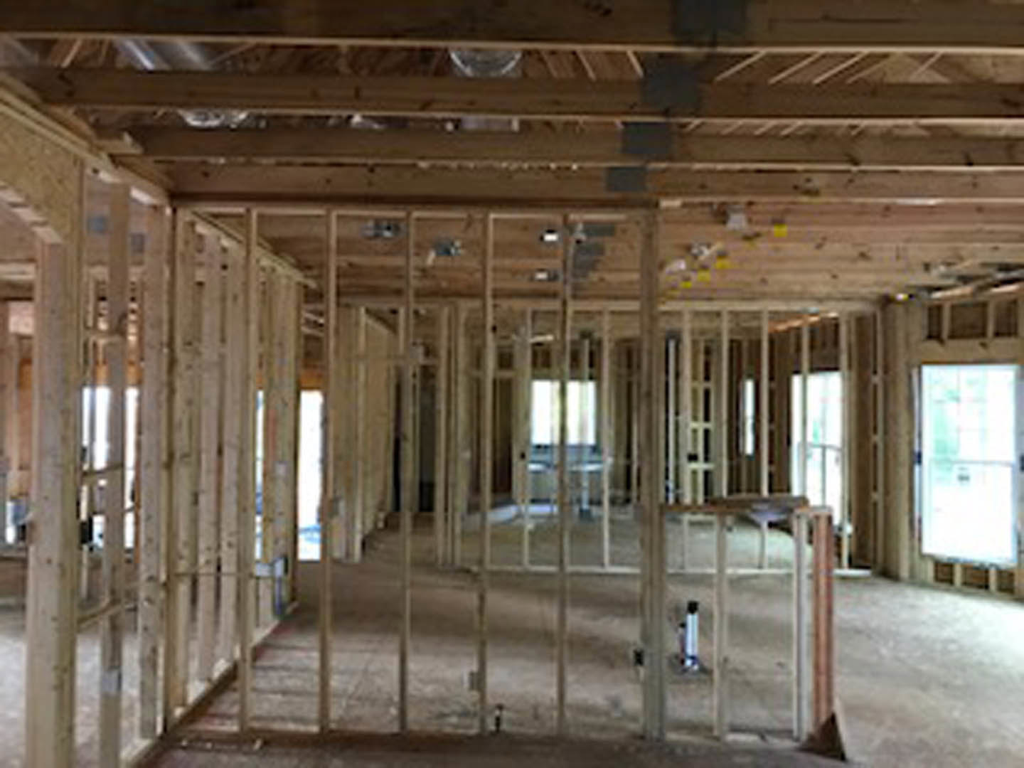 Wood-framed room with exposed beams, unfinished wooden ceiling, and a window letting in daylight
