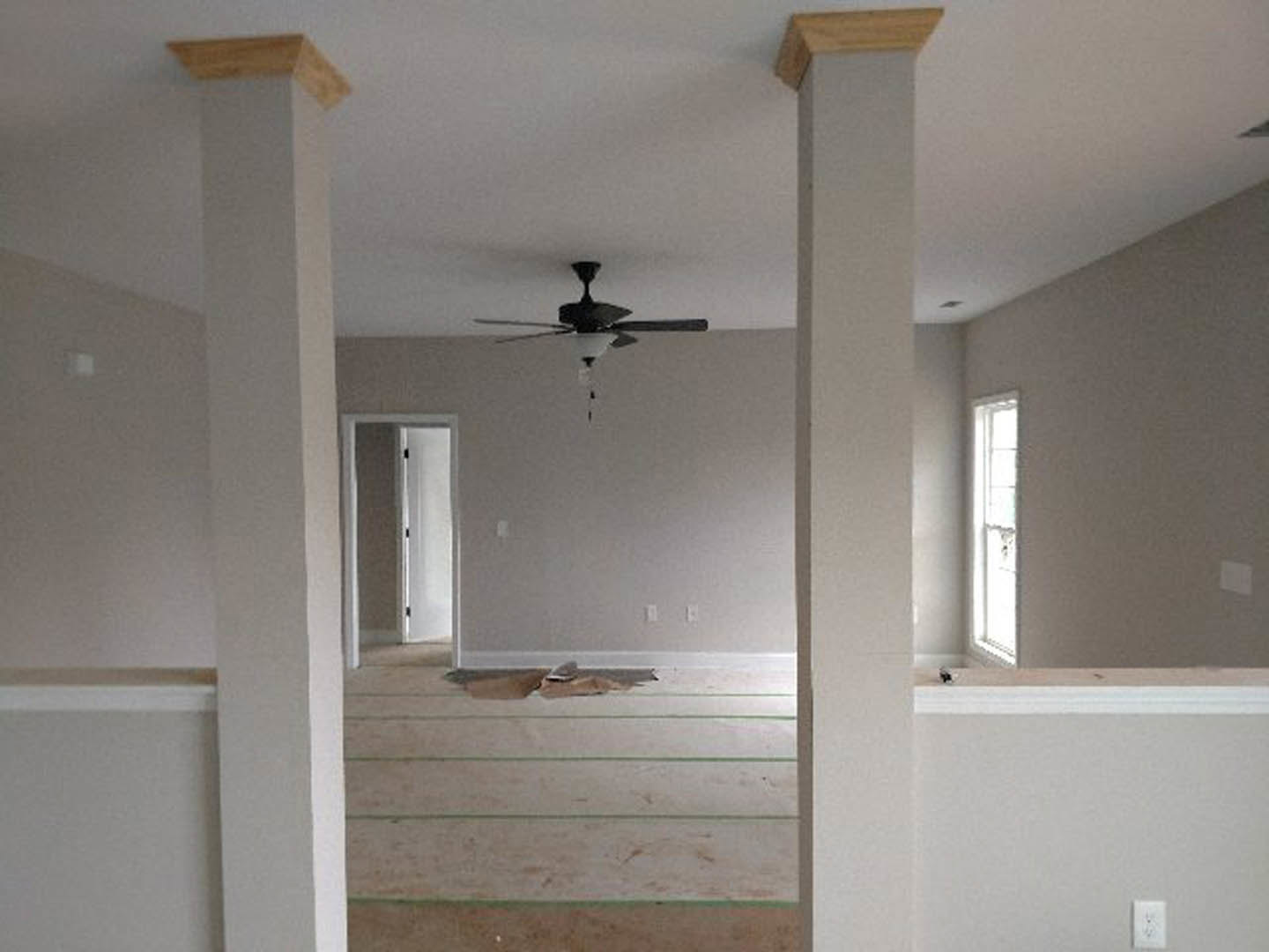 Ceiling fan with integrated light fixture mounted on white plaster ceiling, decorative molding along walls, neutral-toned interior.