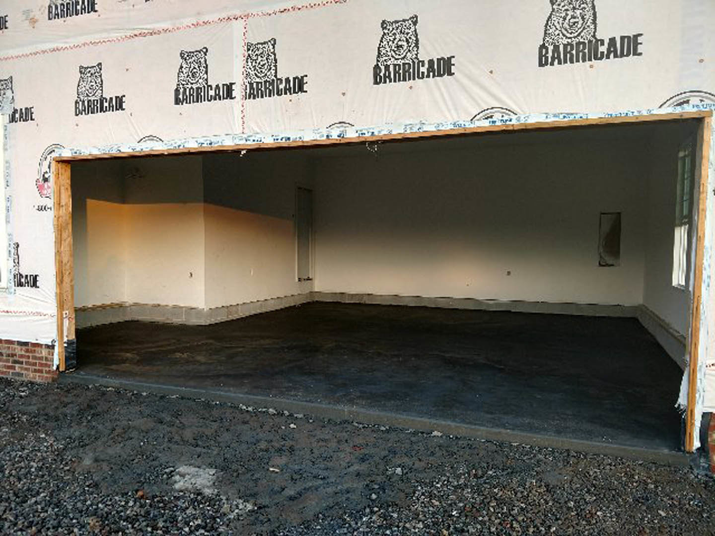 Detached garage with white tarp draped over entrance, concrete floor, white walls, outdoor setting