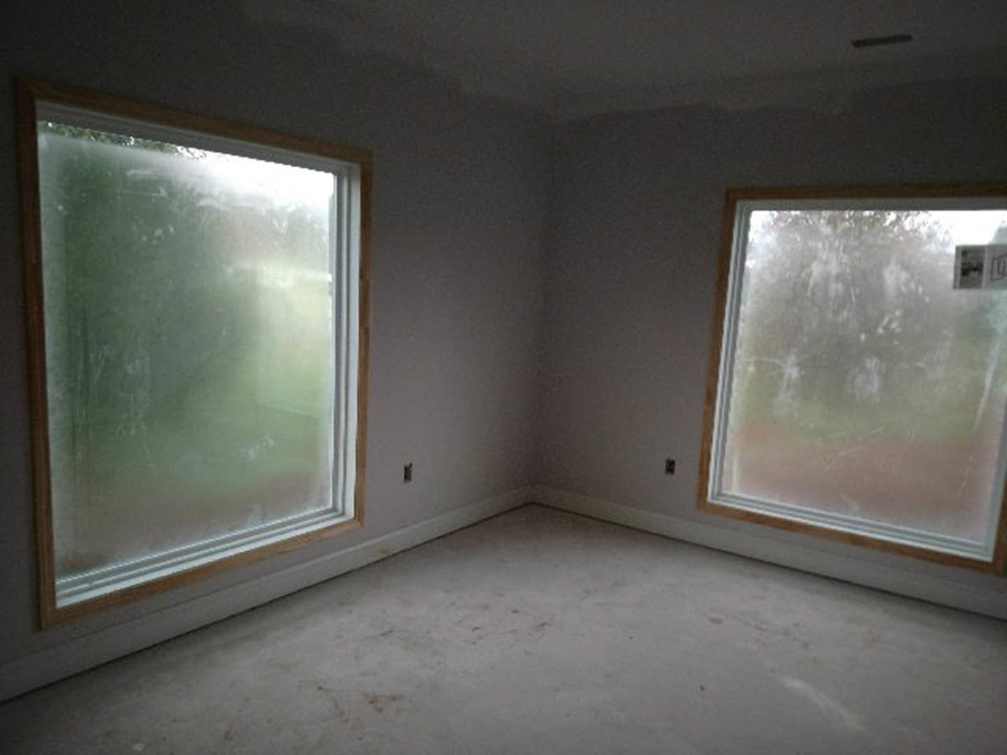 White room with two wood-framed frosted windows, smooth plaster walls, and white flooring.