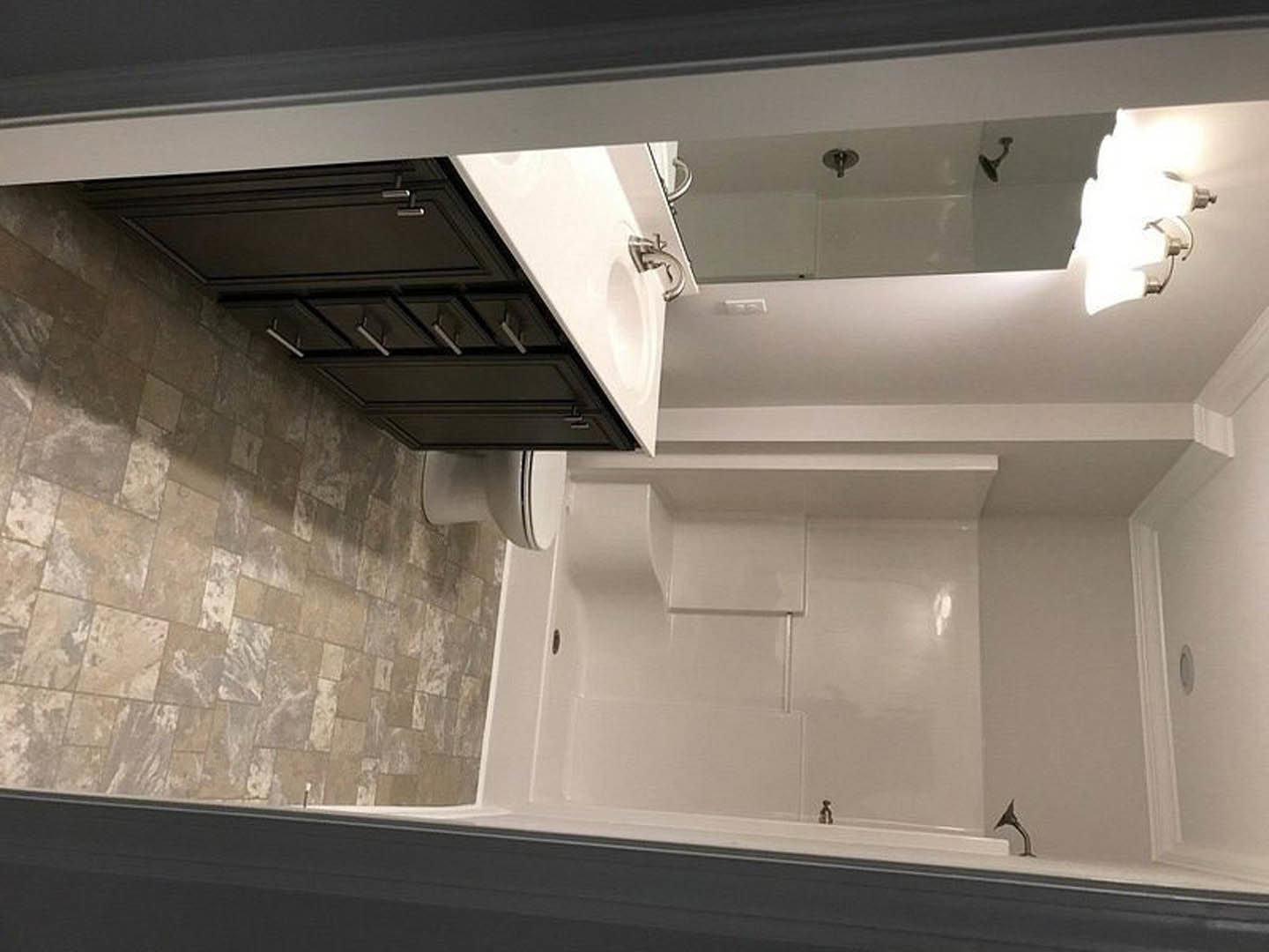 Modern bathroom featuring a white sink and toilet, black vanity cabinet, wall-mounted shower head, and contrasting black and white tile walls.