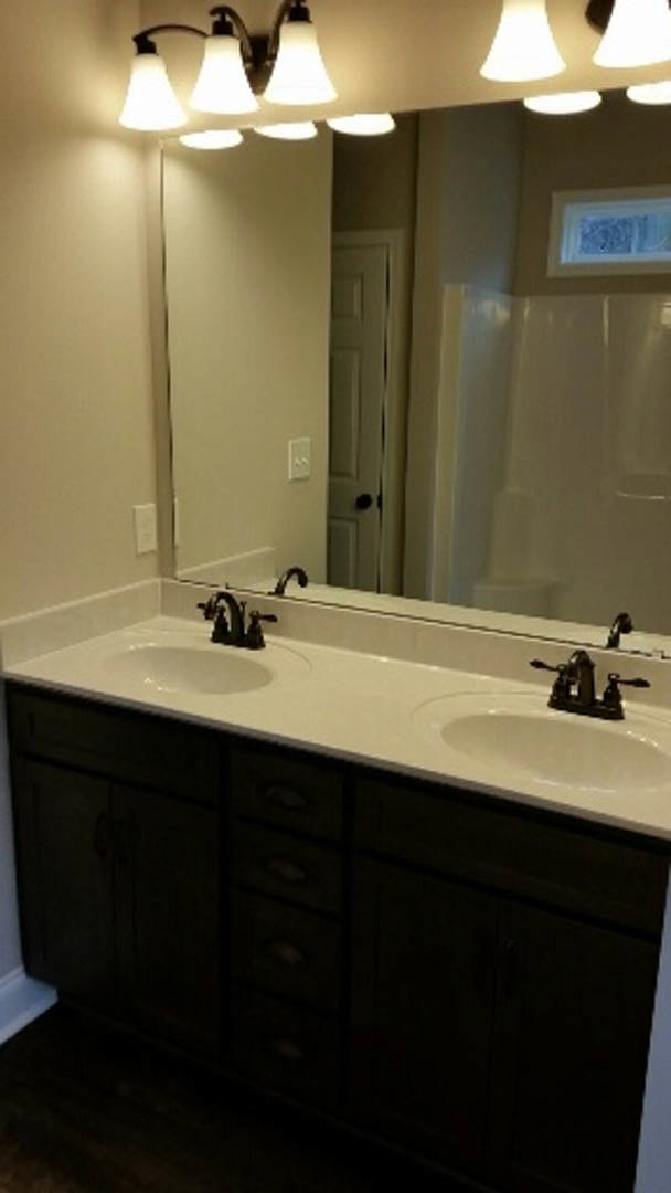 Double vanity with white undermount sinks, chrome faucets, quartz countertop, large framed mirror, and light gray tile backsplash