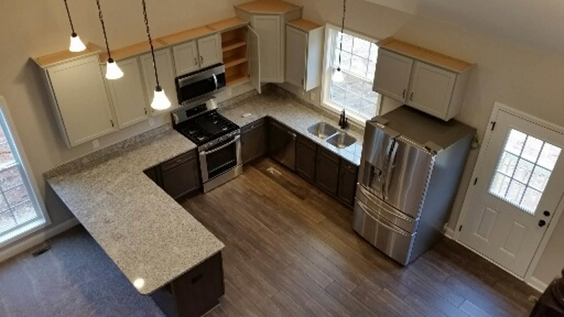 Kitchen with stainless steel refrigerator, wood flooring, white cabinetry, stone countertops, and undermount sink