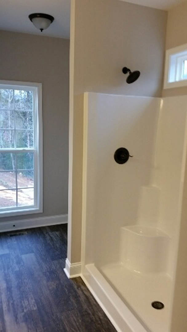 Glass-enclosed shower with chrome fixtures, light gray tile walls, and frosted window providing natural light in modern bathroom
