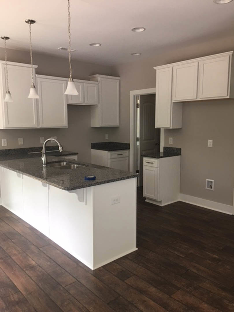 Kitchen with white shaker cabinets, granite countertops, stainless steel faucet, kitchen island, wood flooring, and recessed lighting