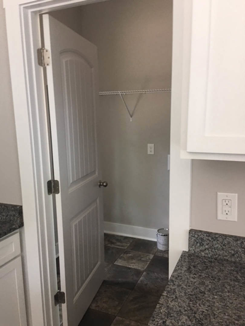 White closet door with brushed metal handle, tile flooring, and adjacent white wall