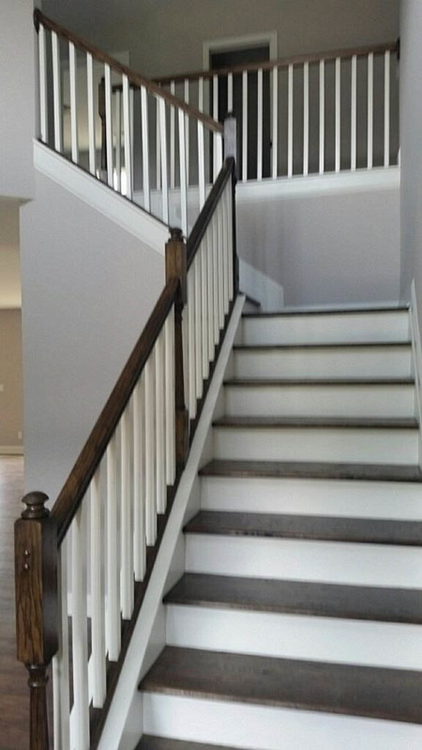 White staircase with wooden handrail, white balusters, and light-colored walls in a modern interior.