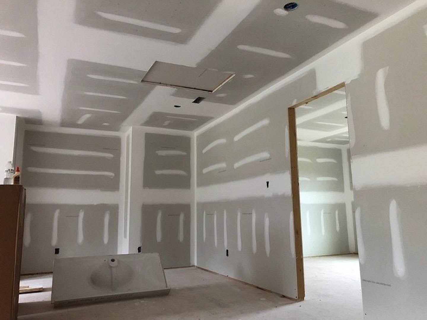 White-walled room featuring two white sinks with chrome faucets, open door, light-colored flooring, and plaster molding along ceiling edges