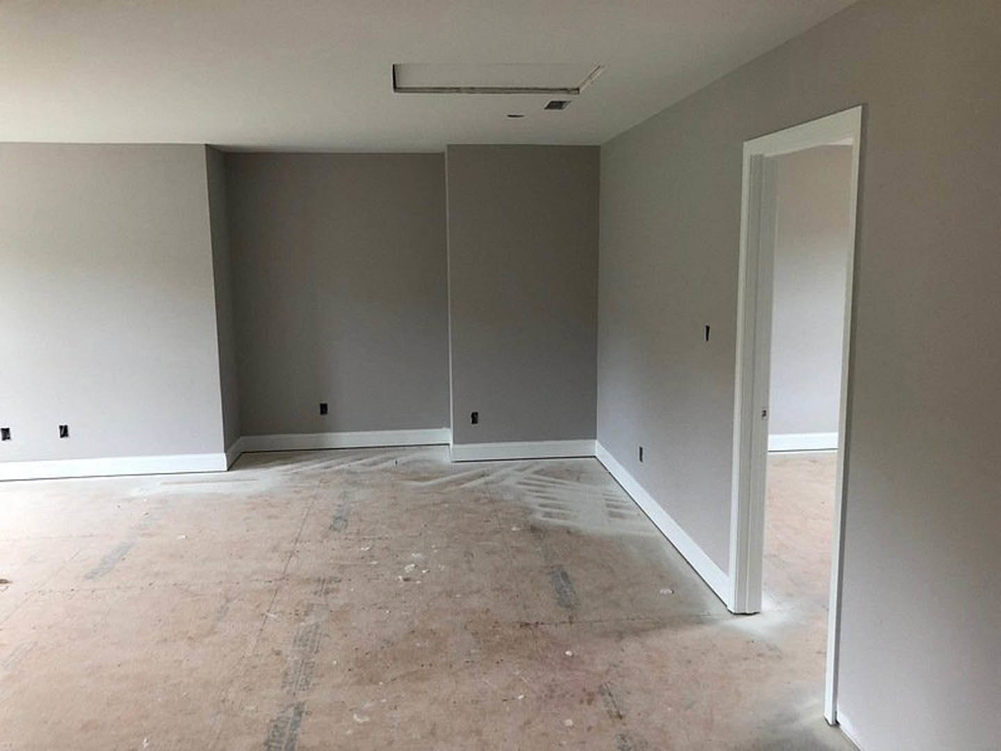 White door with matching frame open to a room featuring white walls with black trim, tile flooring with scattered white paint, and ceiling plaster.