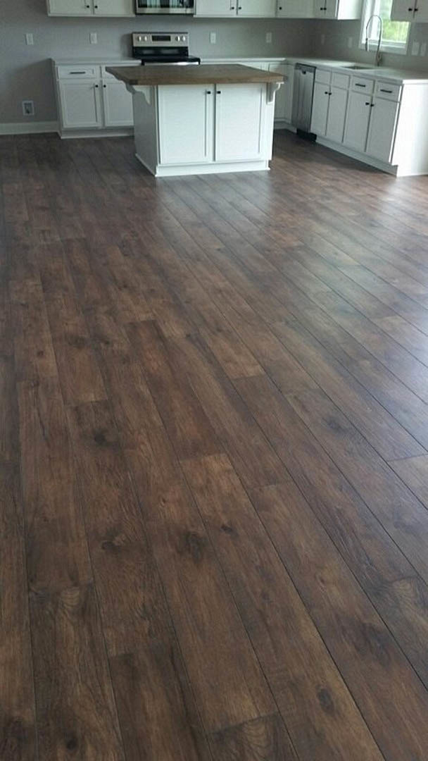 Wood floor with white walls, white door featuring a black handle, white kitchen island topped with wood.