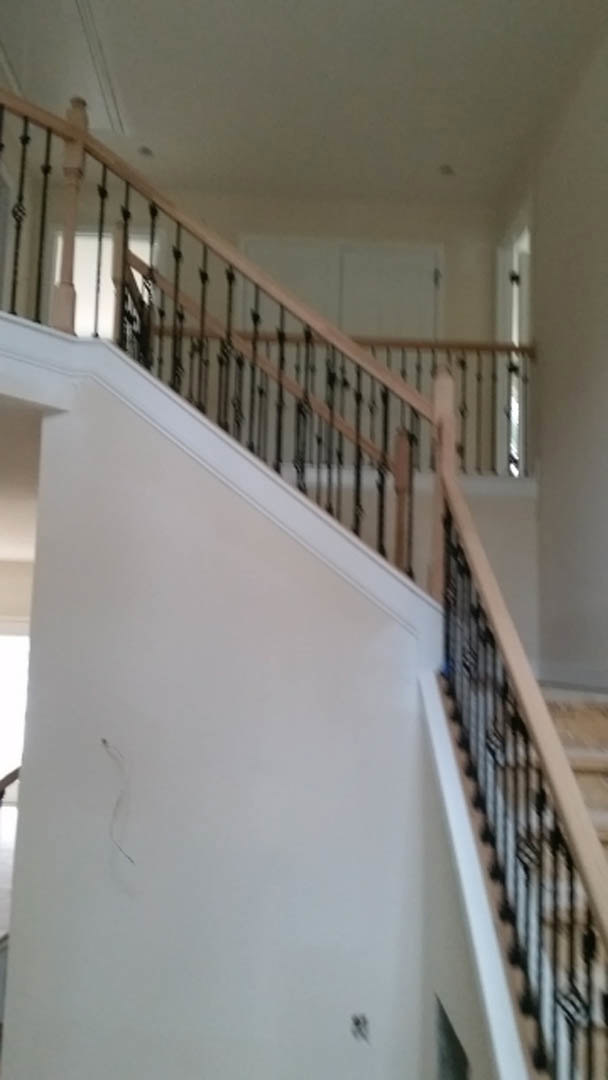 Modern staircase with sleek metal railings against a white wall, featuring wood steps and minimalist design