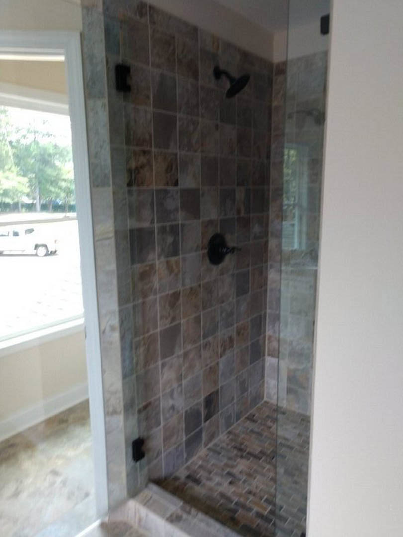 Walk-in shower with clear glass door, marble tile walls, and tile flooring in a modern bathroom