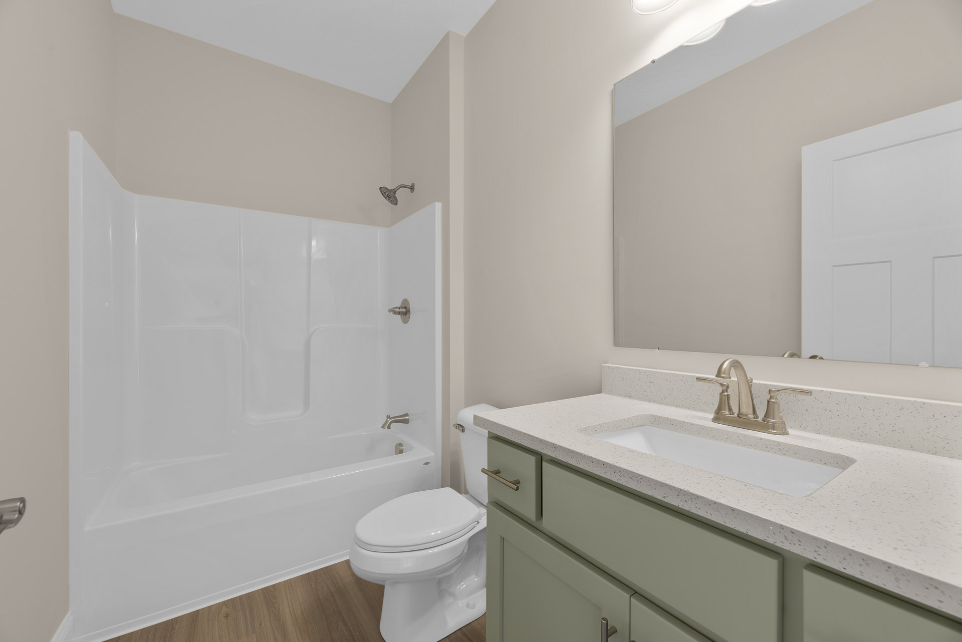 White bathtub, toilet with closed lid, and rectangular sink on stone countertop; wall-mounted faucet, tiled walls, and paneled white door in modern bathroom.