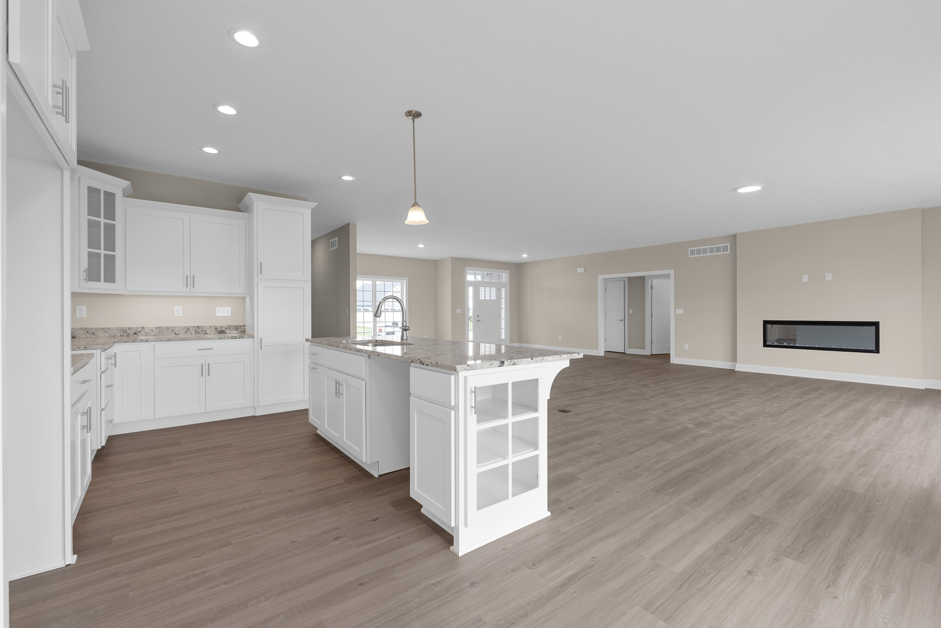 Spacious open-concept kitchen with white island, glass shelves, wood flooring, black-framed accents, white walls, modern faucet, and multiple doorways