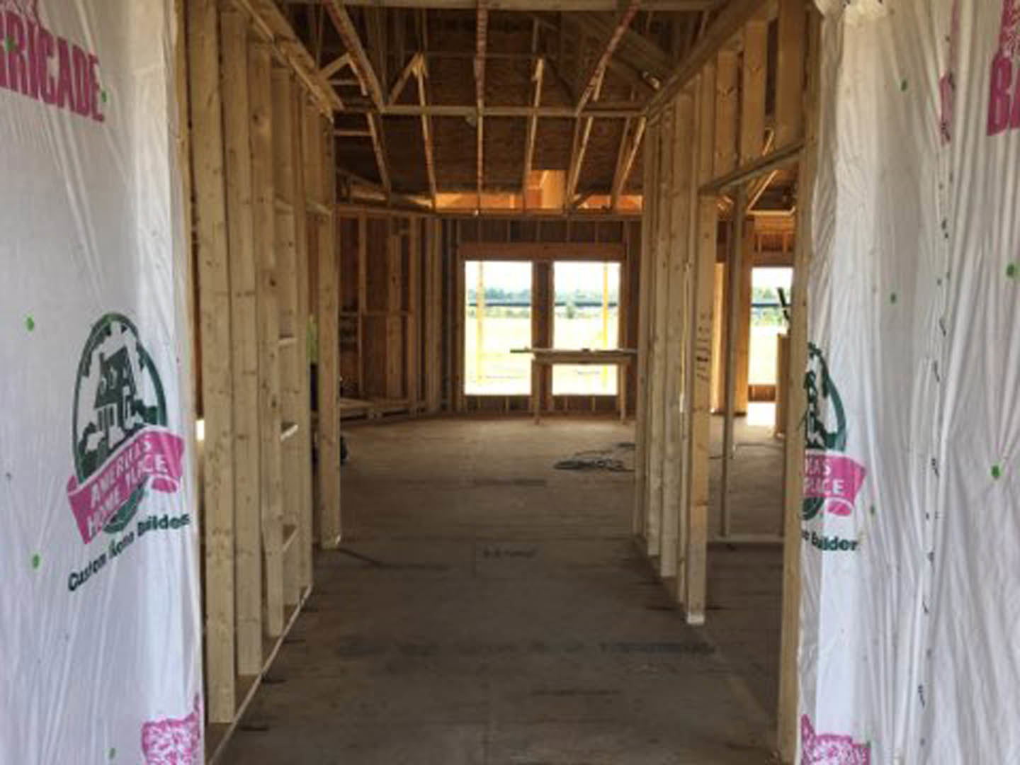 Wood-framed interior under construction with exposed beams, unfinished walls, and a window providing natural light
