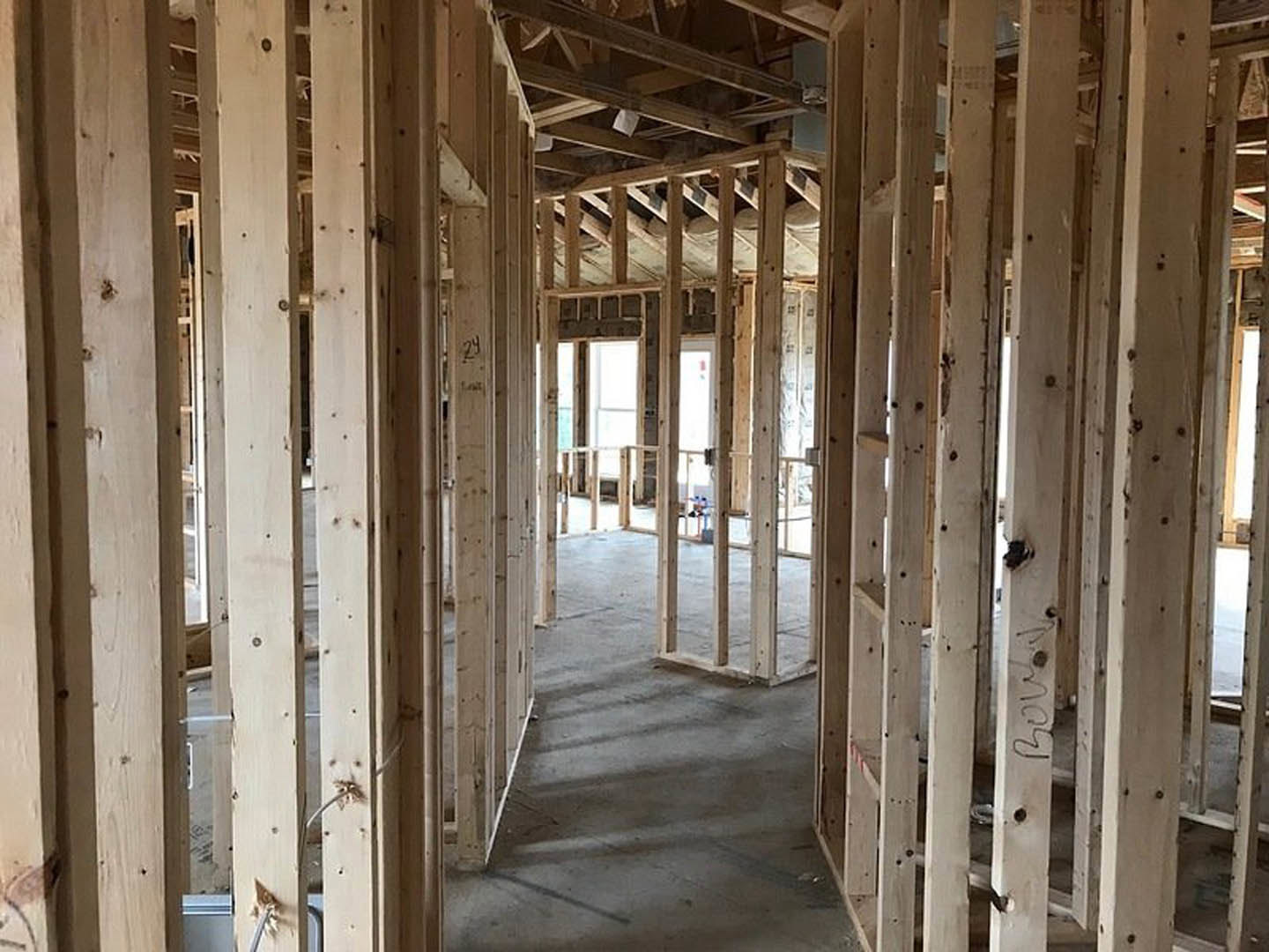 Wood framing and exposed beams in a room under construction with a concrete floor