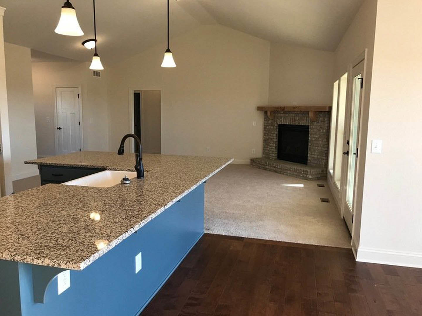 Marble kitchen island with built-in sink, white cabinetry, tile flooring, fireplace with black surround, and white door with black handle