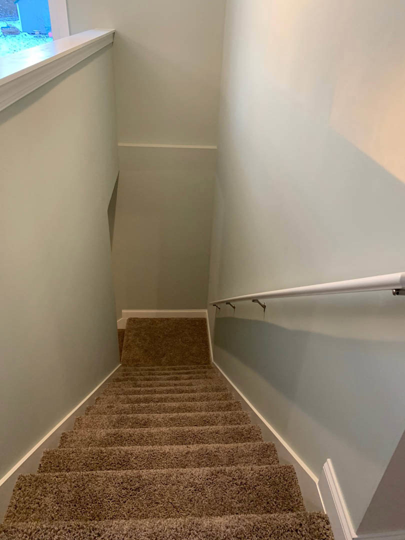 Carpeted staircase with white railing, blue accent wall, window ledge, and plaster ceiling