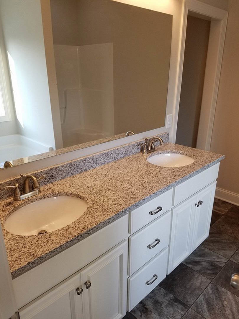 Bathroom with white cabinets, marble countertop, large wall mirror, chrome faucet, and black-bordered sink