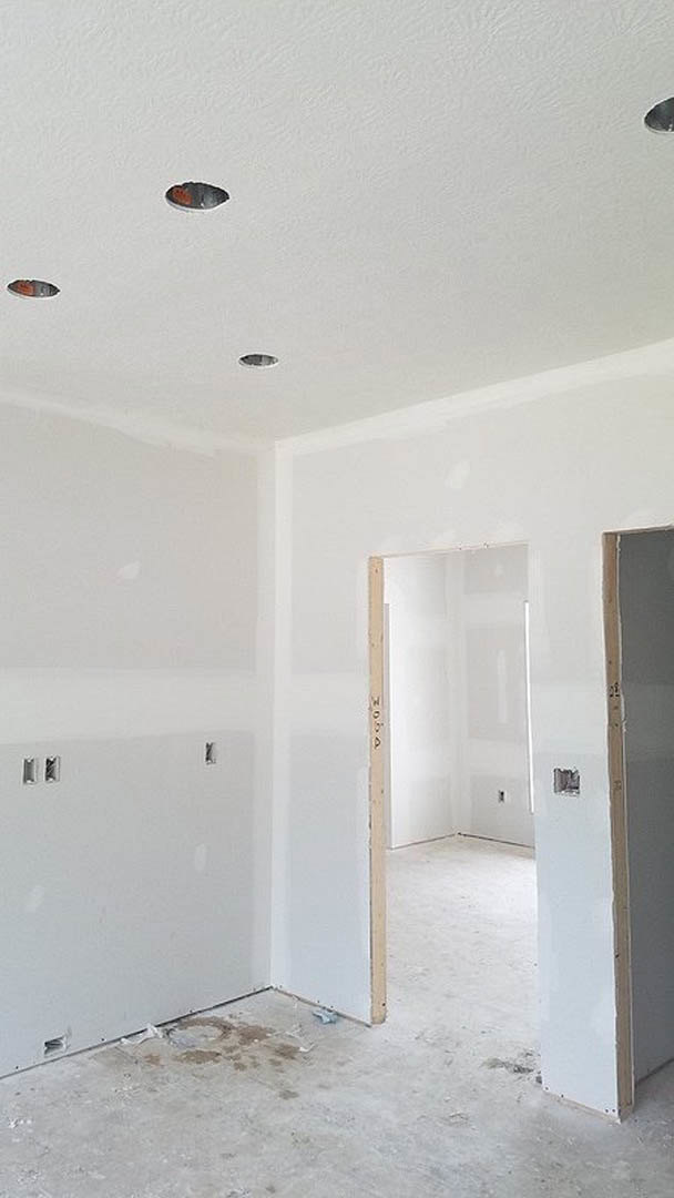White walls, open door, white cabinet, white frame, and visible holes in plaster wall; light flooring and ceiling in a modern indoor room.
