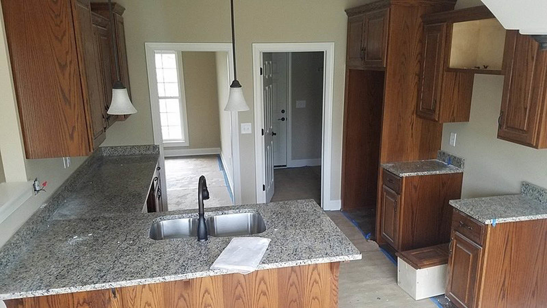 Kitchen with granite countertops, tile flooring, white cabinetry, stainless steel sink, and a black appliance on the floor