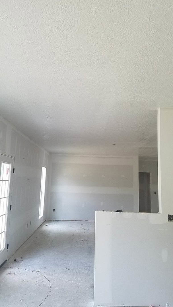 White-walled room with white ceiling, white door featuring a black handle, circular snow pattern visible outside