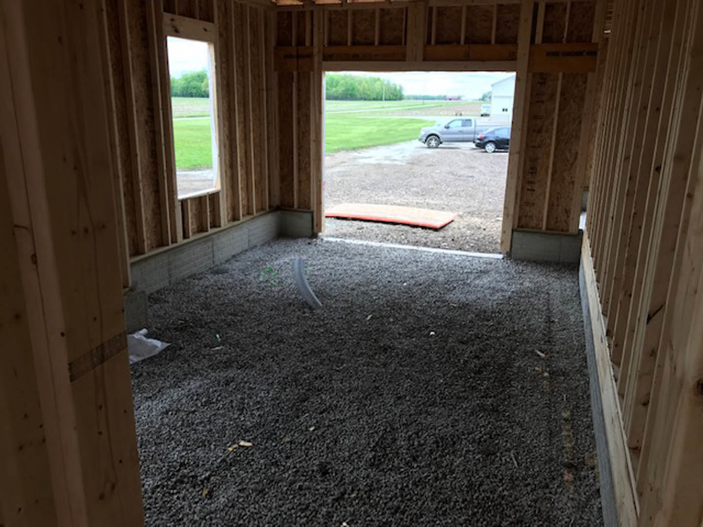 Black gravel floor with a red mat in the background, wood plank walls, and natural light illuminating the interior space