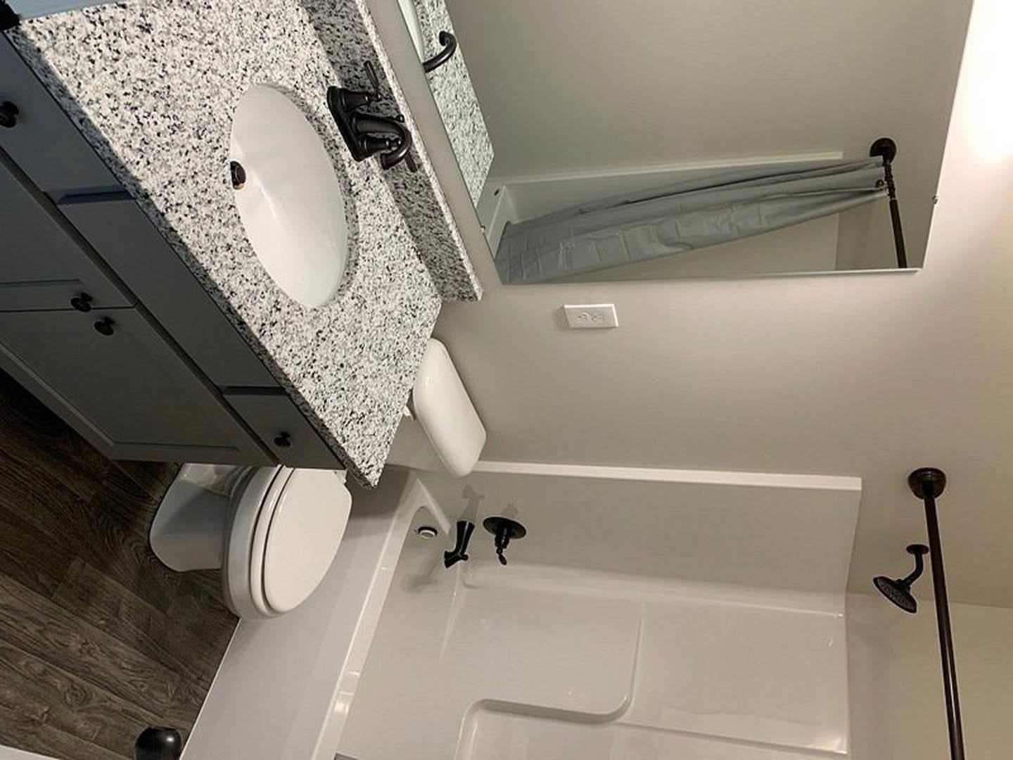 Modern bathroom with white bathtub, wall-mounted sink, and toilet, surrounded by light tile walls and flooring, chrome fixtures, and a large mirror above the vanity