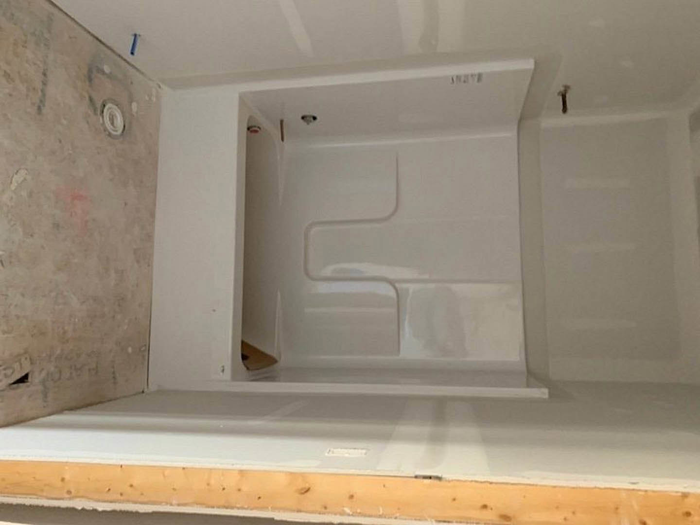 White tiled shower with built-in niche, smooth plaster walls, marble floor, and recessed ceiling lighting.