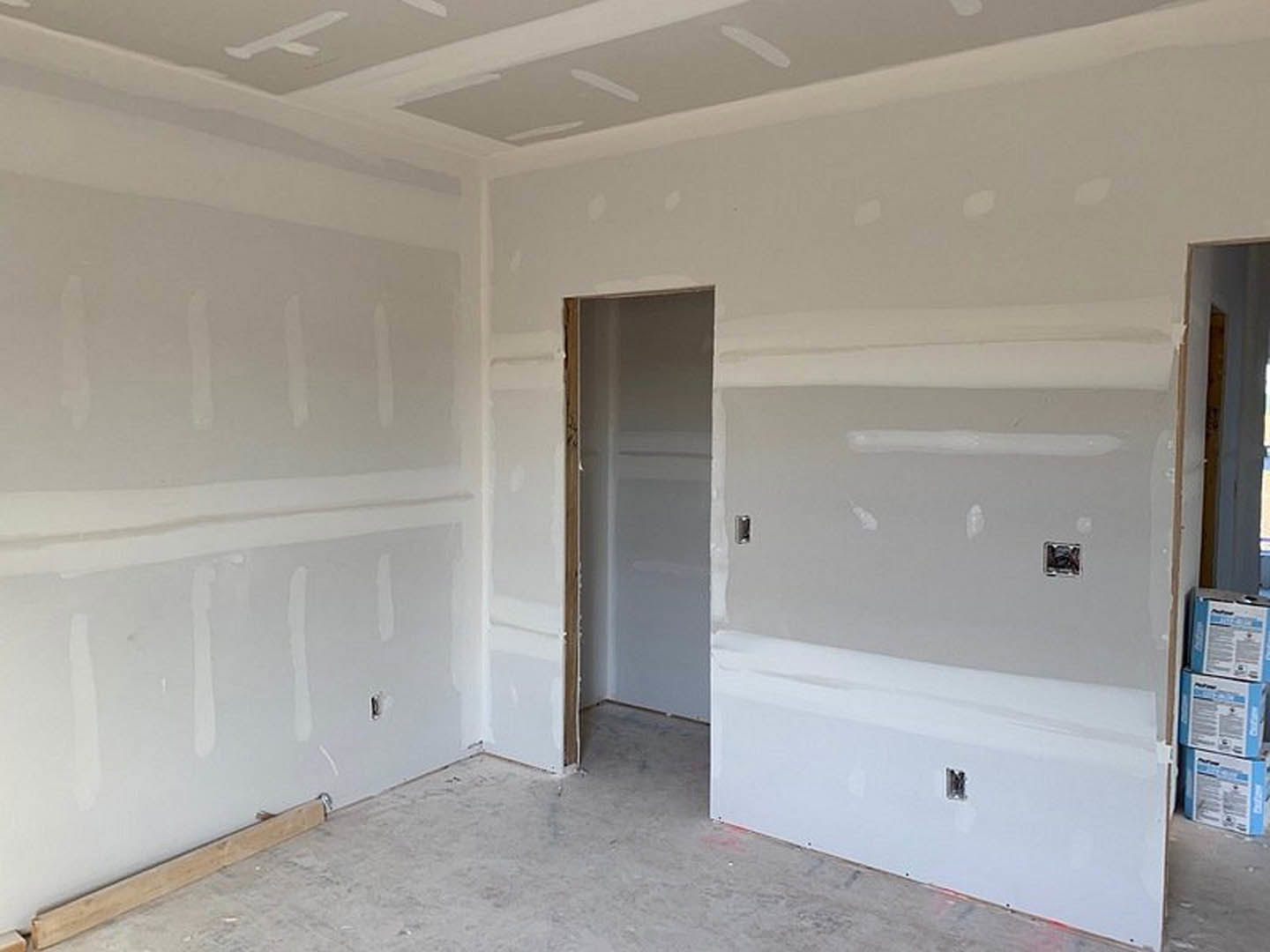 White walls with marble flooring, wooden door frame, visible molding, and a power outlet on the wall.