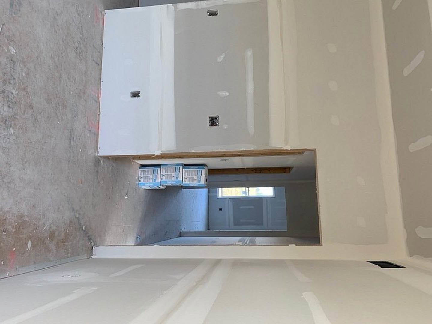 White-walled room featuring a doorway, a closed door, a window with a shelf below, white cabinetry with silver hinges, and a built-in microwave.